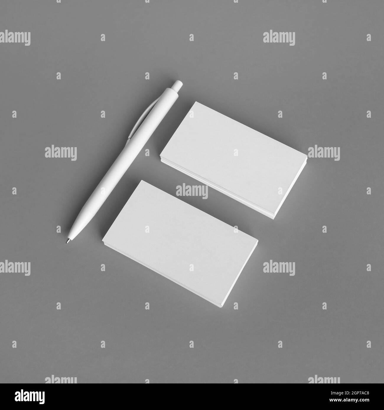Blank business cards and pen on gray paper background. Branding mock up. Stock Photo