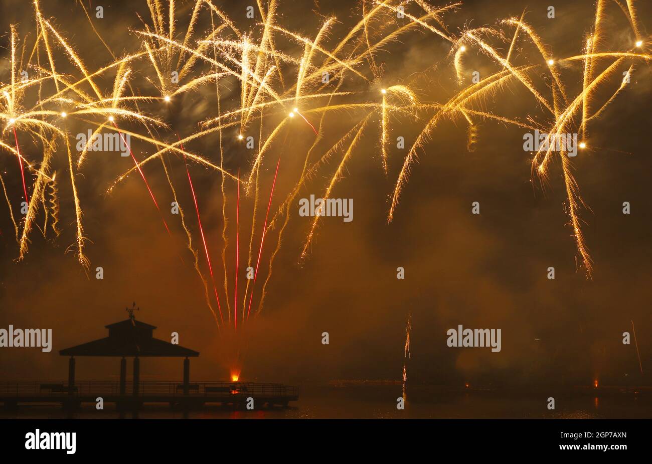 Fireworks at Delco Park. Fishing pier and pavilion silhouette in foreground of ground display fireworks. Delco Park, Kettering, Dayton, Ohio, USA. Stock Photo