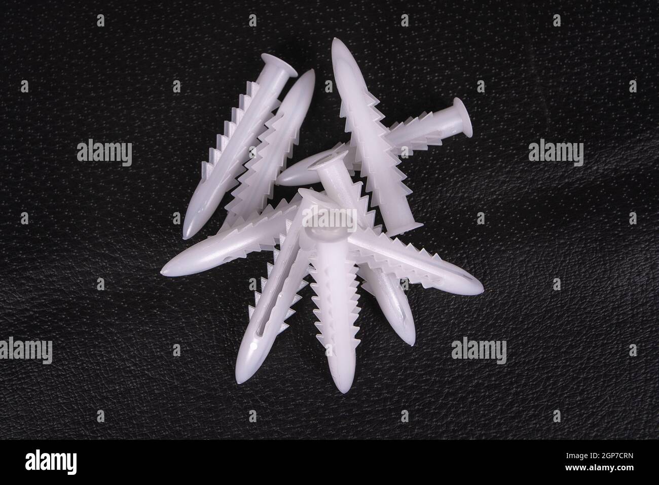 A group of plastic anchors on a black surface Stock Photo