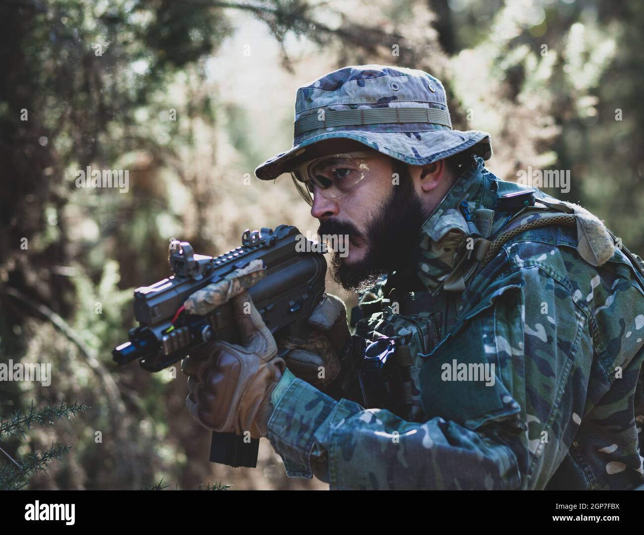 Airsoft military game player in camouflage uniform with armed assault rifle. Stock Photo