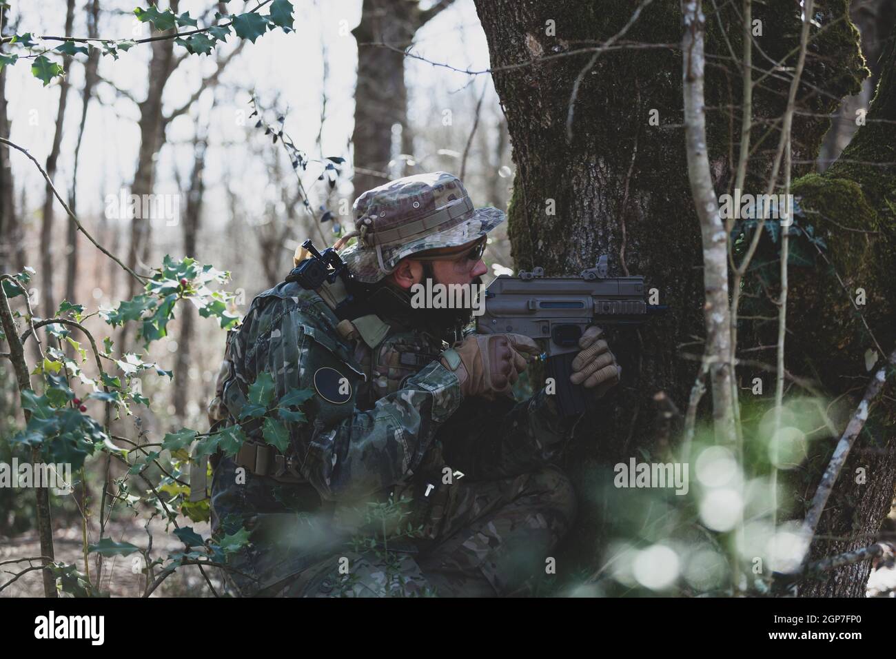 Airsoft military game player in camouflage uniform with armed assault rifle. Stock Photo