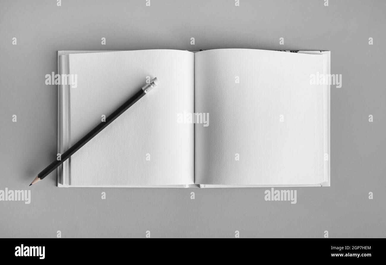 Blank sketchbook and pencil mock up on gray paper background. Top view