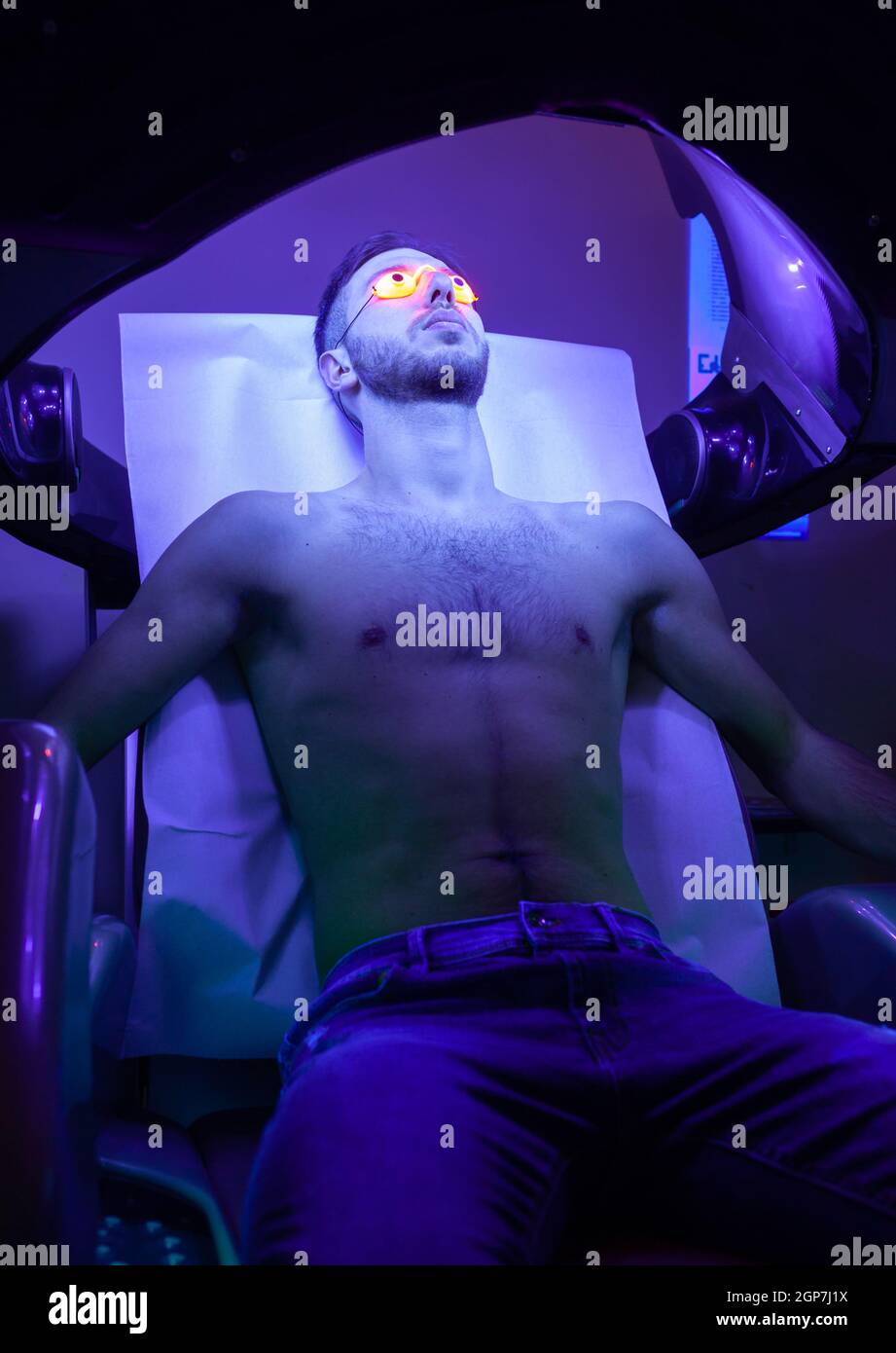 Young Thin Man At Solarium In Beauty Salon. Stock Photo