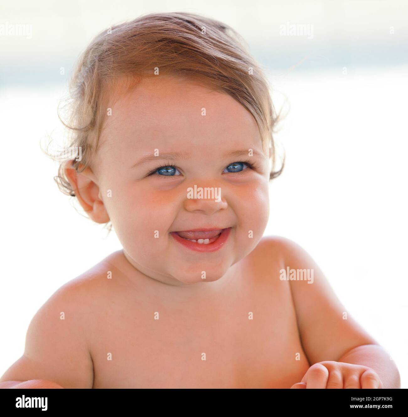 Portrait at the beach of a smiling one year old baby girl with blue