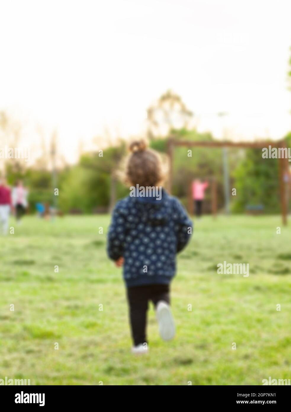 Blurred shot .Little girl runs from behind in the park playing with other children. Stock Photo