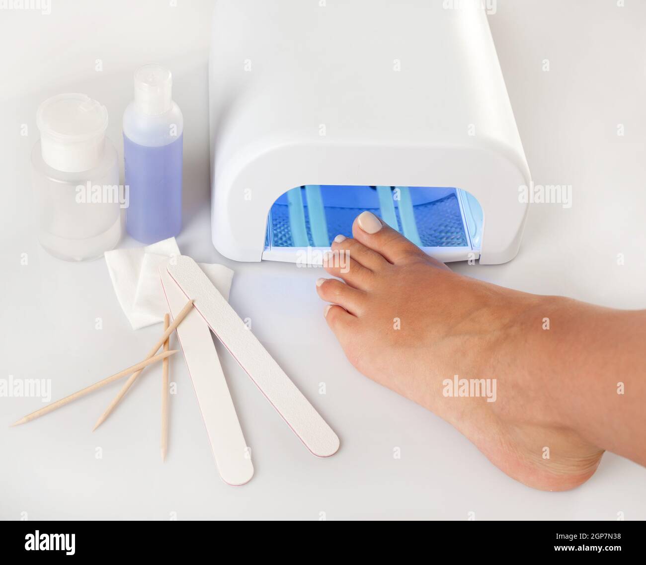 Pedicure foot and nail treatment with cosmetic products and UV lamp