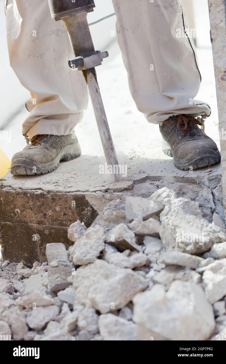 Worker demolishing the concrete with a jackhammer. Stock Photo