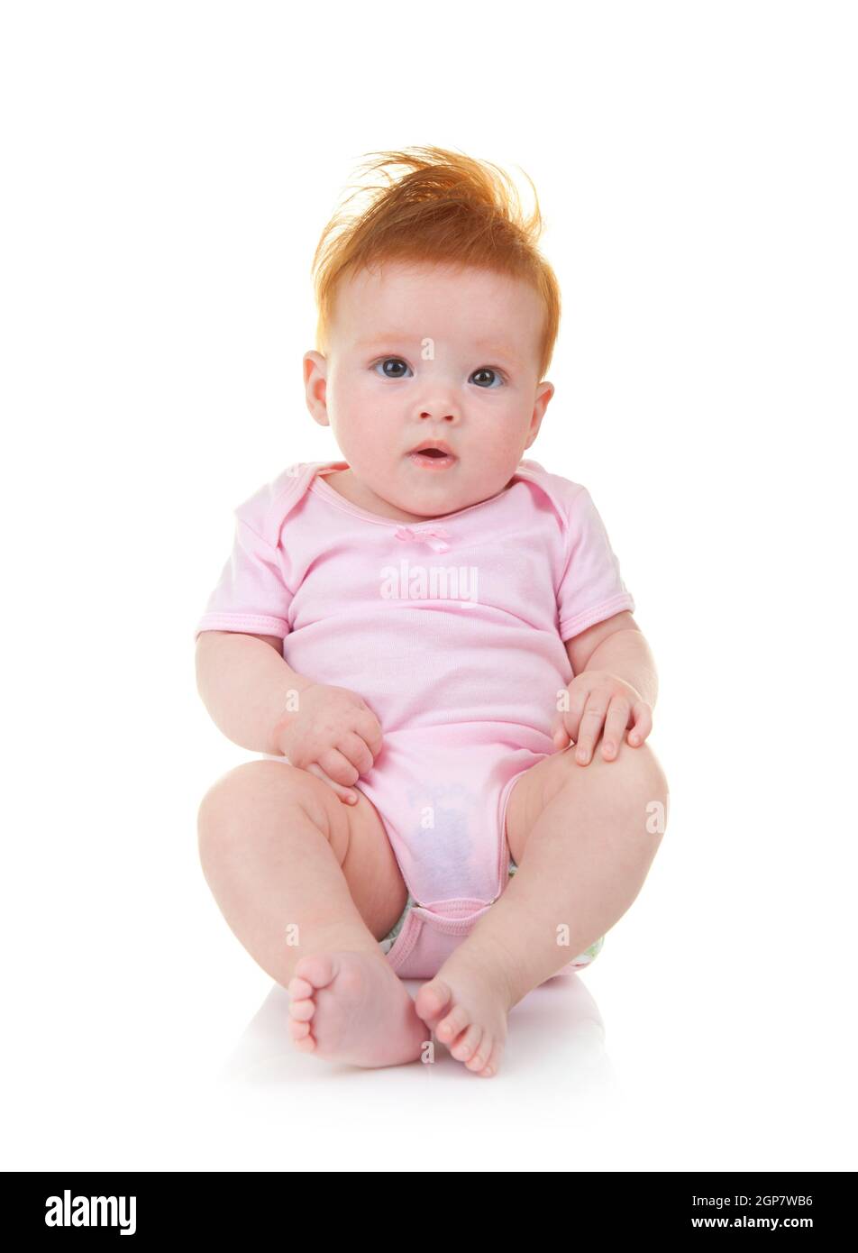 Smiling baby in pink jumpsuit sitting on the floor isolated on white background Stock Photo