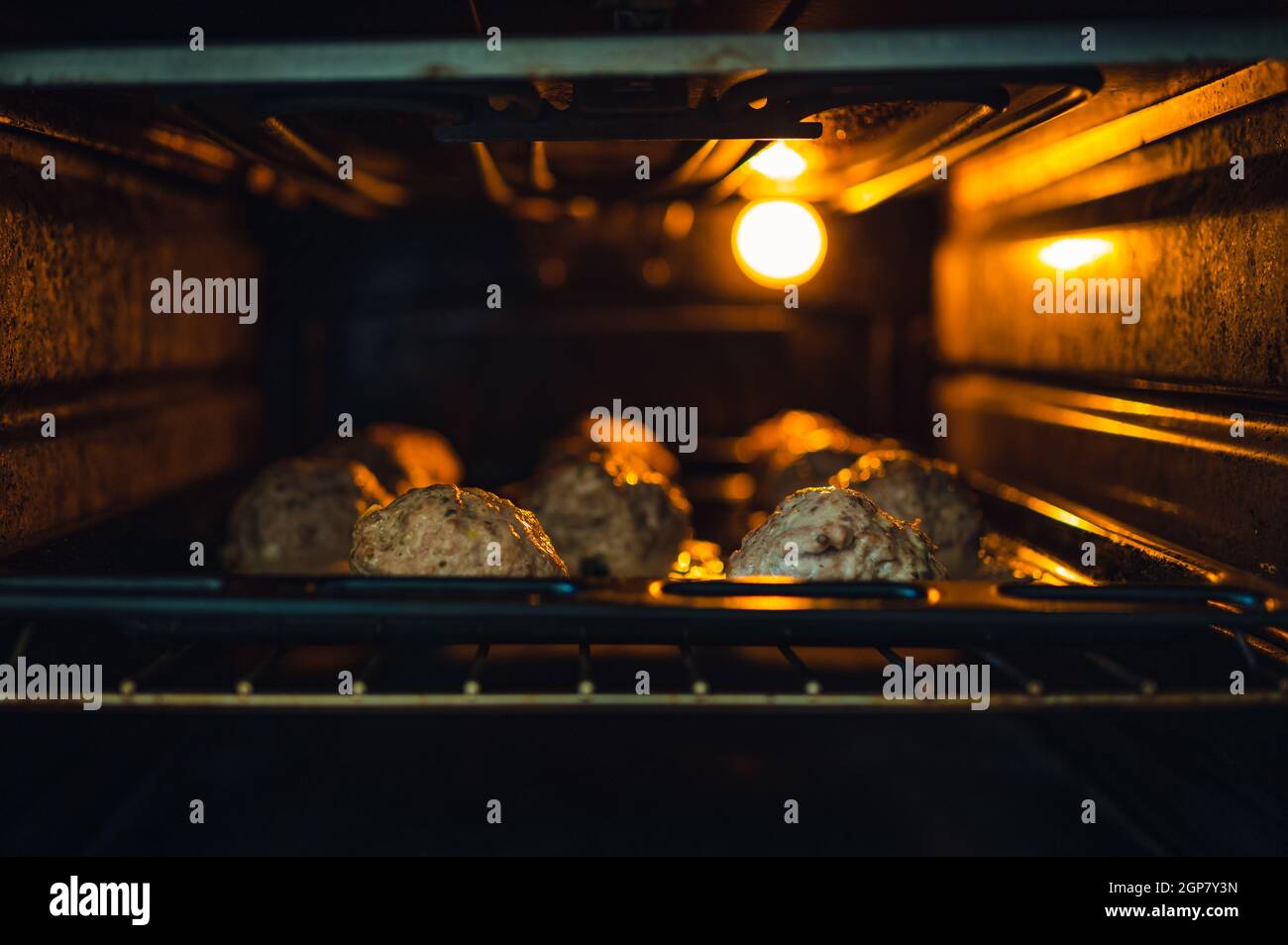 View into the oven on the baking tray for meatballs. Little light, light only from the oven. Shallow depth of field, blurred background. Stock Photo