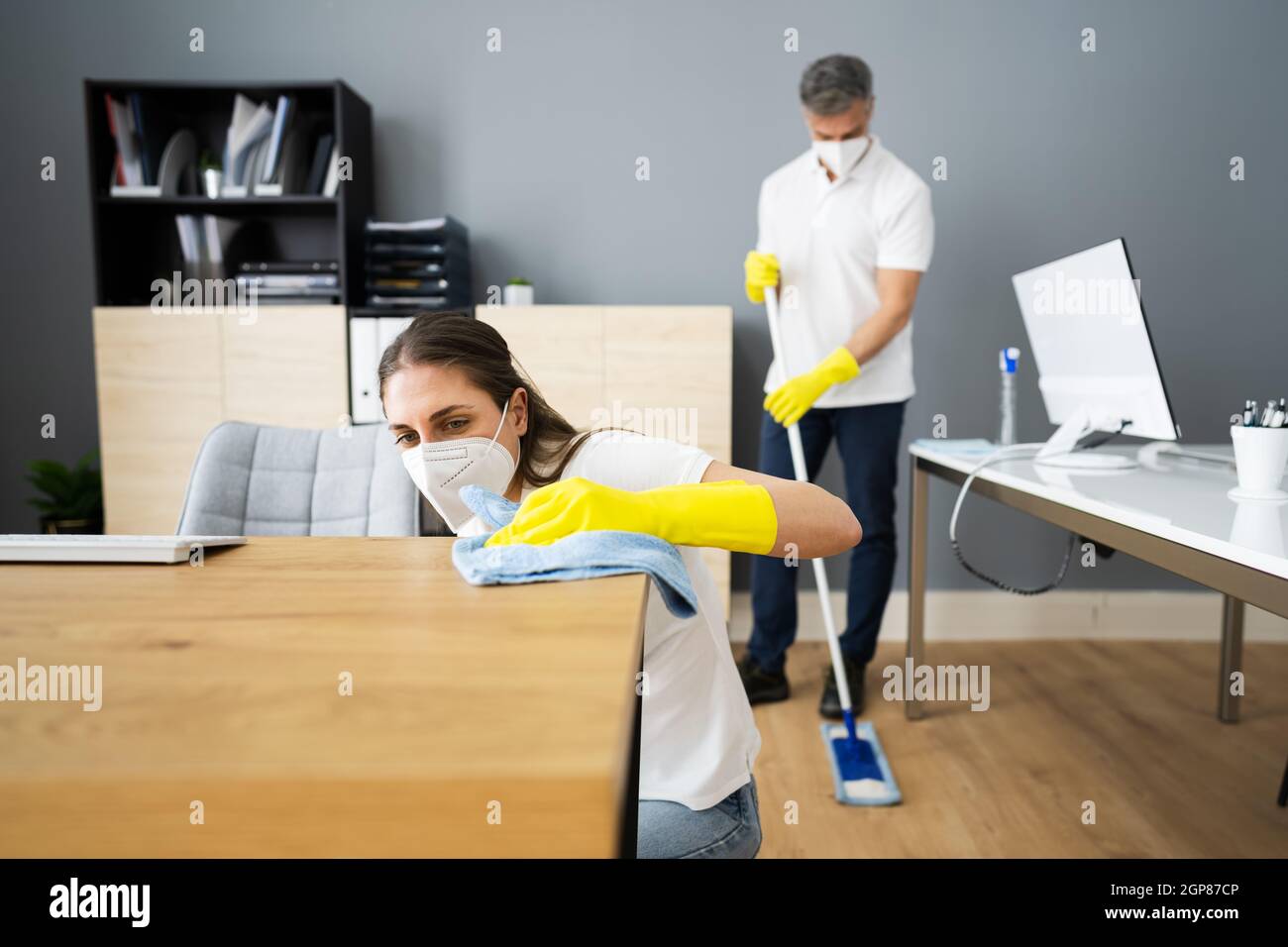 Janitor Cleaner Woman In Face Mask Cleaning Desk Stock Photo