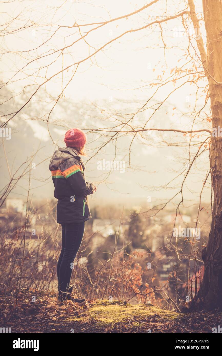 Young standing girl is enjoying the sunset scenery, winter time Stock Photo