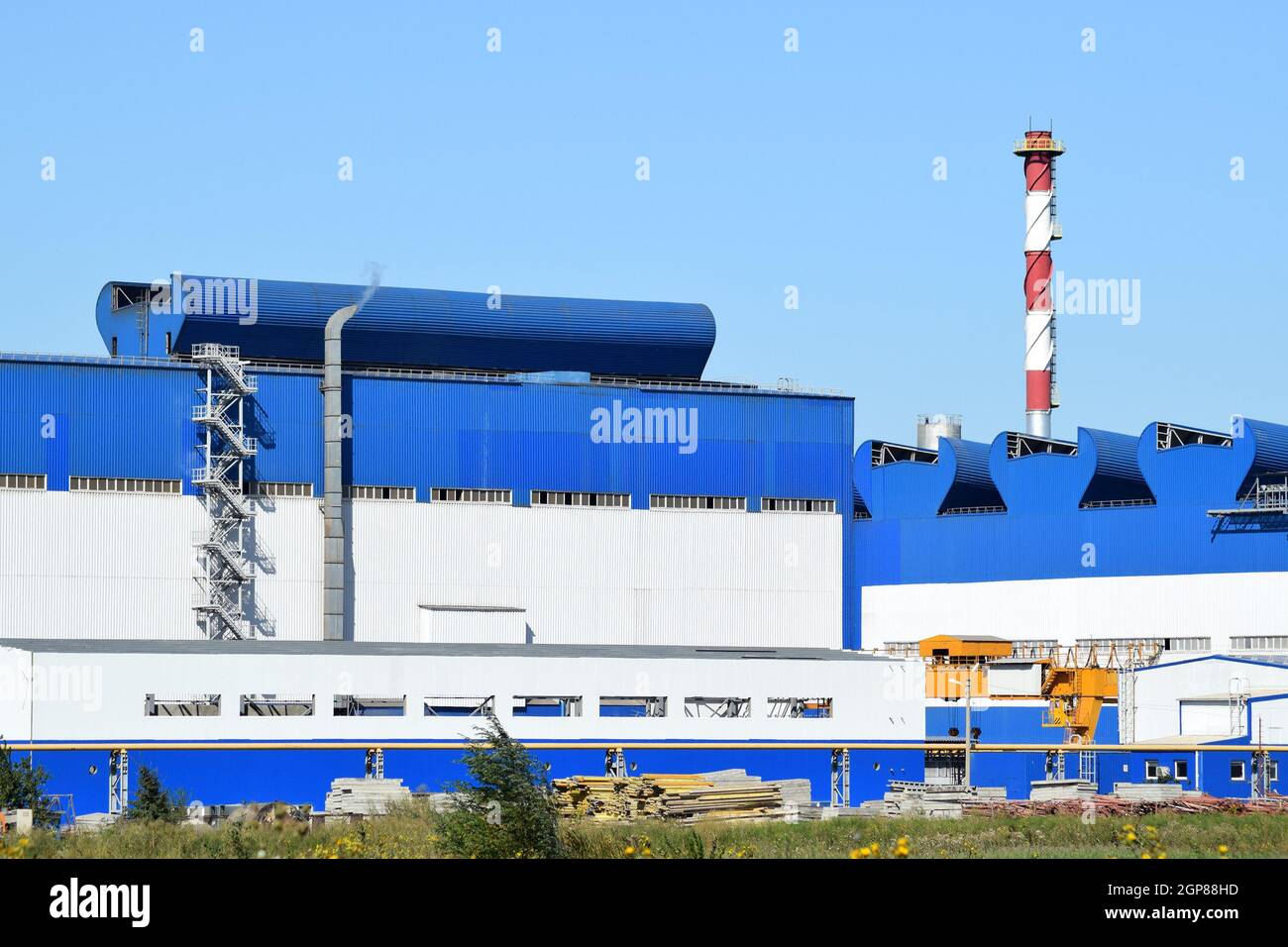Big plant for processing scrap metal. Huge factory old metal refiner. Blue roof of the factory building. Exhaust pipes, radiators, cooling industrial Stock Photo