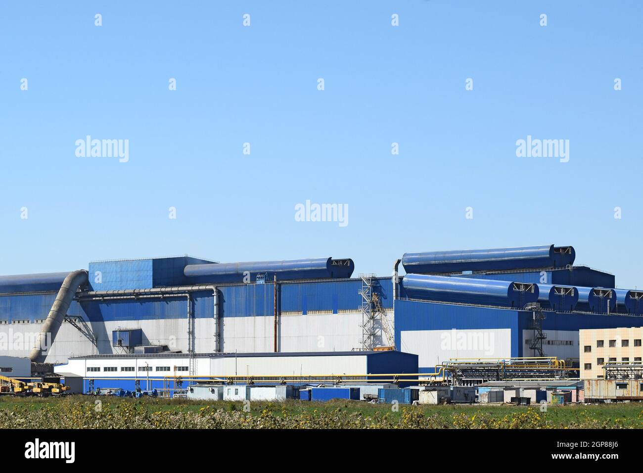 Big plant for processing scrap metal. Huge factory old metal refiner. Blue roof of the factory building. Exhaust pipes, radiators, cooling industrial Stock Photo