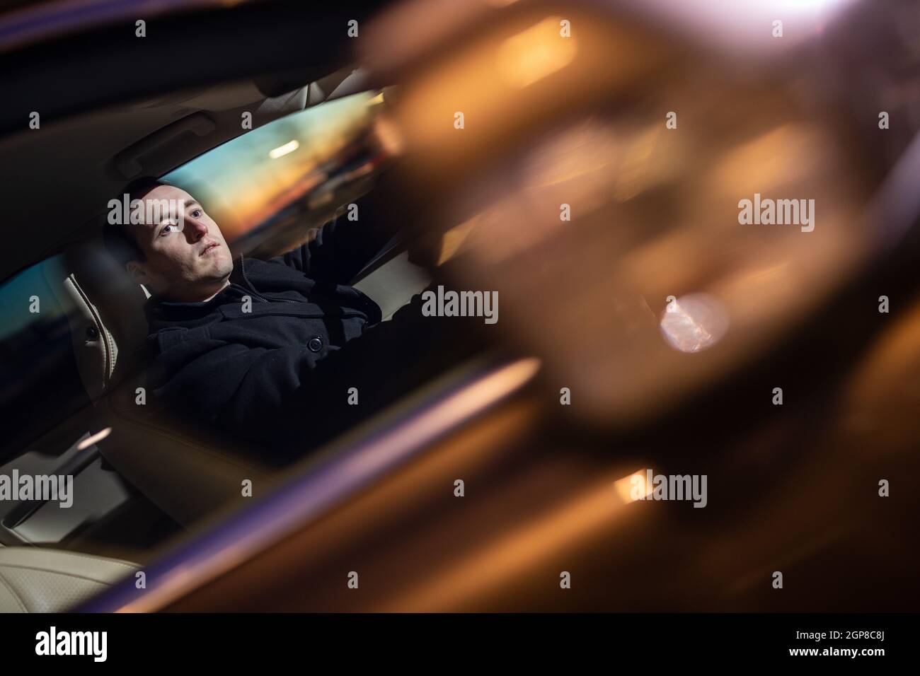 Handsome young man driving his car at night (color toned image; motion ...
