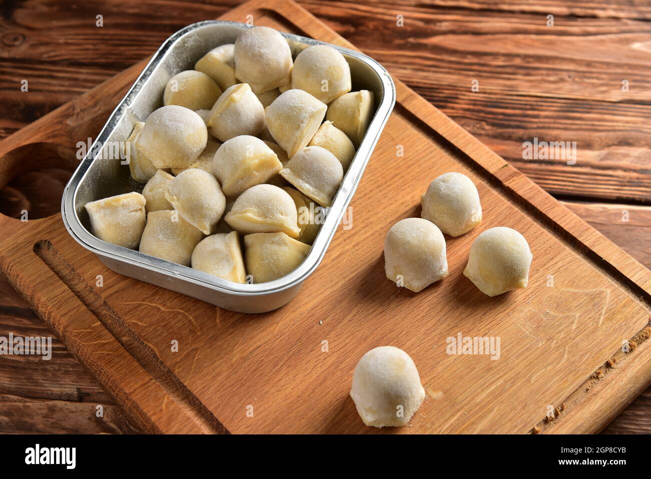 Frozen homemade raw food of ravioli on wooden board table. Stock Photo