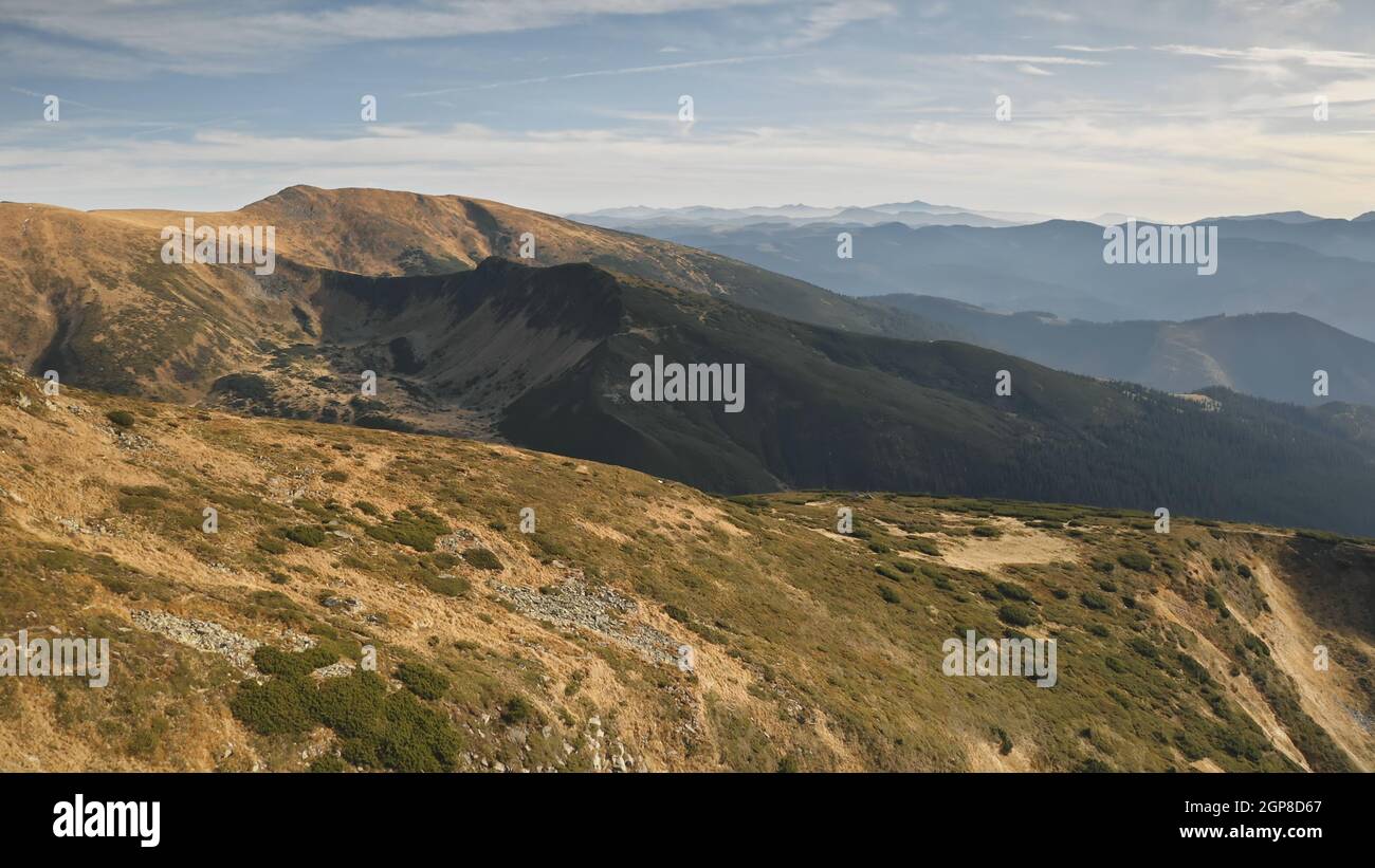 Aerial mountain ridges. Rock mount top at high altitude. Nobody nature landscape. Green grass at brown peak. Mountaineering vacation at autumn. Carpathians, Ukraine, Europe. Cinematic drone shot Stock Photo