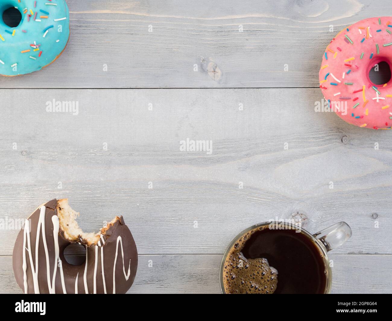 Top view of assorted donuts and coffee on gray wooden background with ...