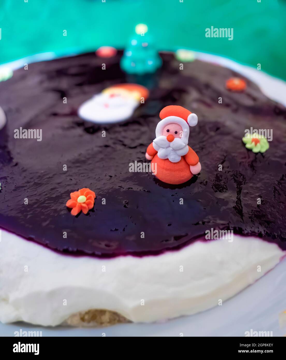 homemade cheese and jam cake decorated with christmas motifs, a Santa Claus figure, an unfocused christmas tree and some flowers, christmas dessert, Stock Photo