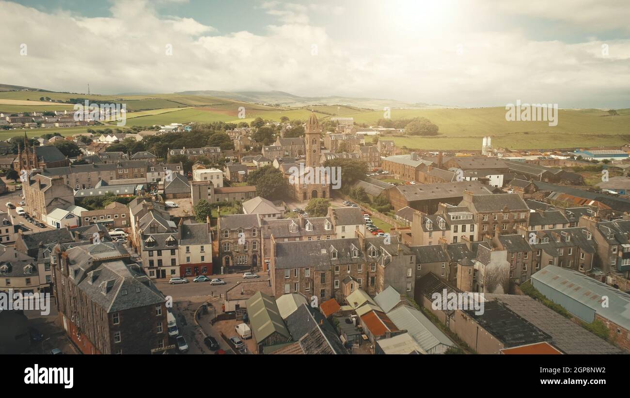 Sun cityscape at traffic road cars drives aerial. Historic buildings at streets of Campbeltown city, Scotland, Europe. Downtown houses and architecture landmark. Cinematic sunlight urban scenery Stock Photo