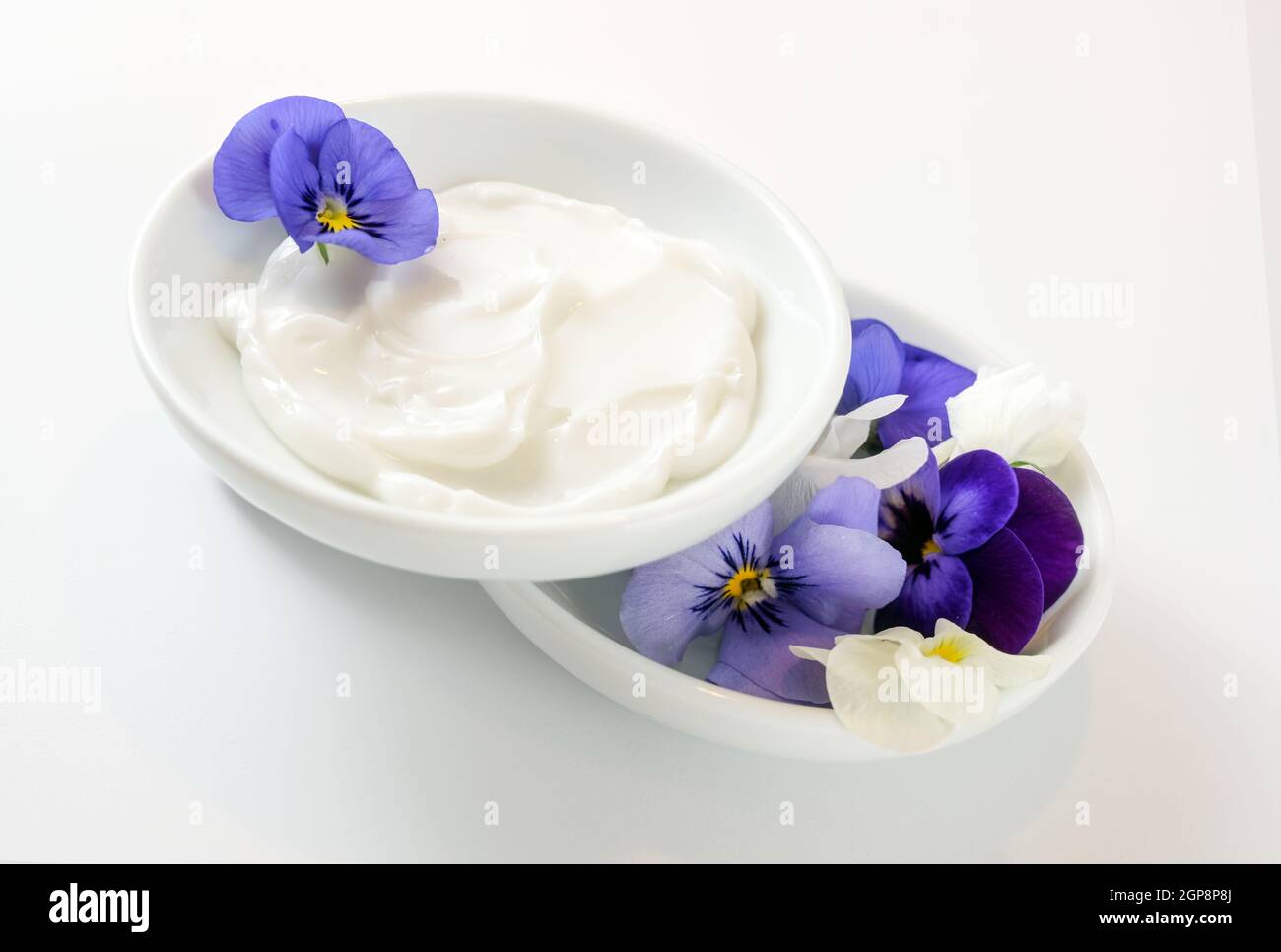 Ointment from viola or violet flowers in white bowls, natural cosmetics concept, white gray background, copy space, selected focus, narrow depth of fi Stock Photo