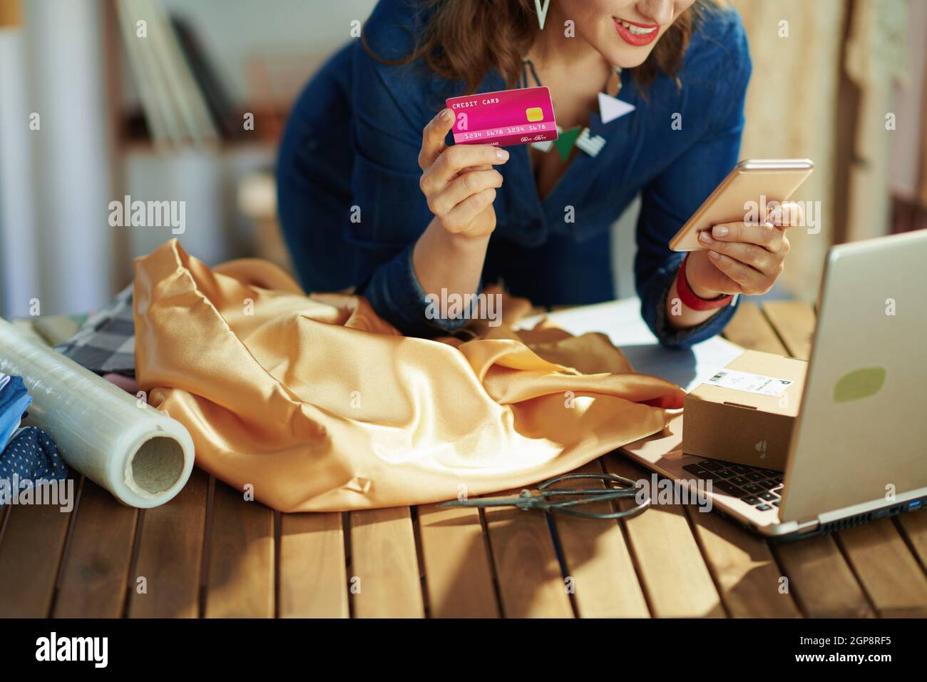 Closeup on small business owner woman with credit card using smartphone in the office. Stock Photo