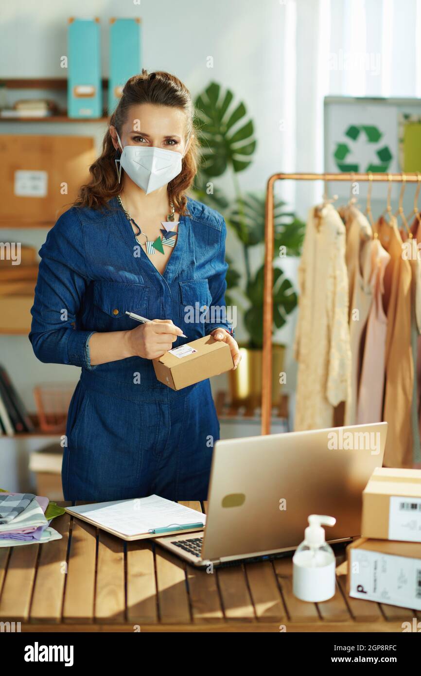 elegant small business owner woman with ffp2 mask, laptop and antiseptic in the office. Stock Photo