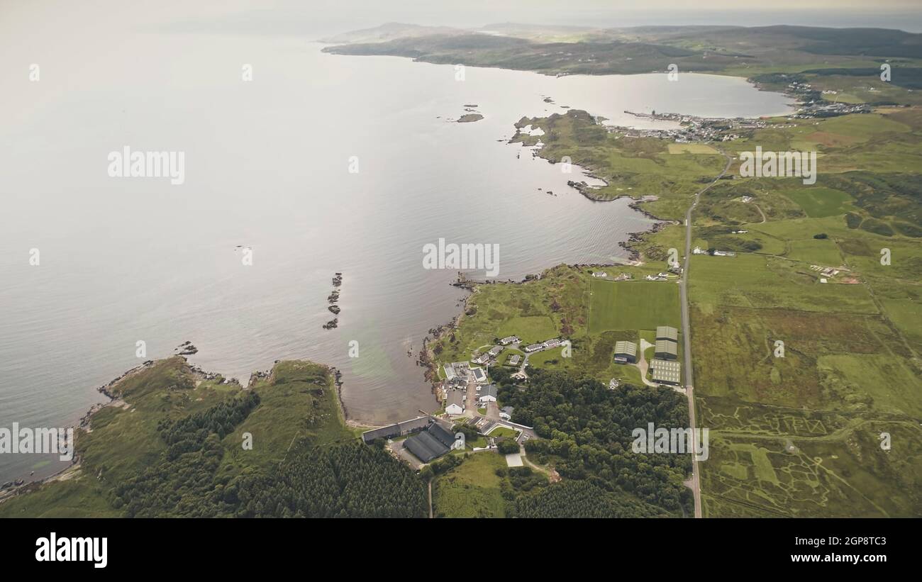 Top down factory at seascape. Aerial nobody nature landscape. Green forest at grass valley. Countryside fields, pastures at sea bay of port town Ellen, Islay Island, United Kingdom, Europe Stock Photo