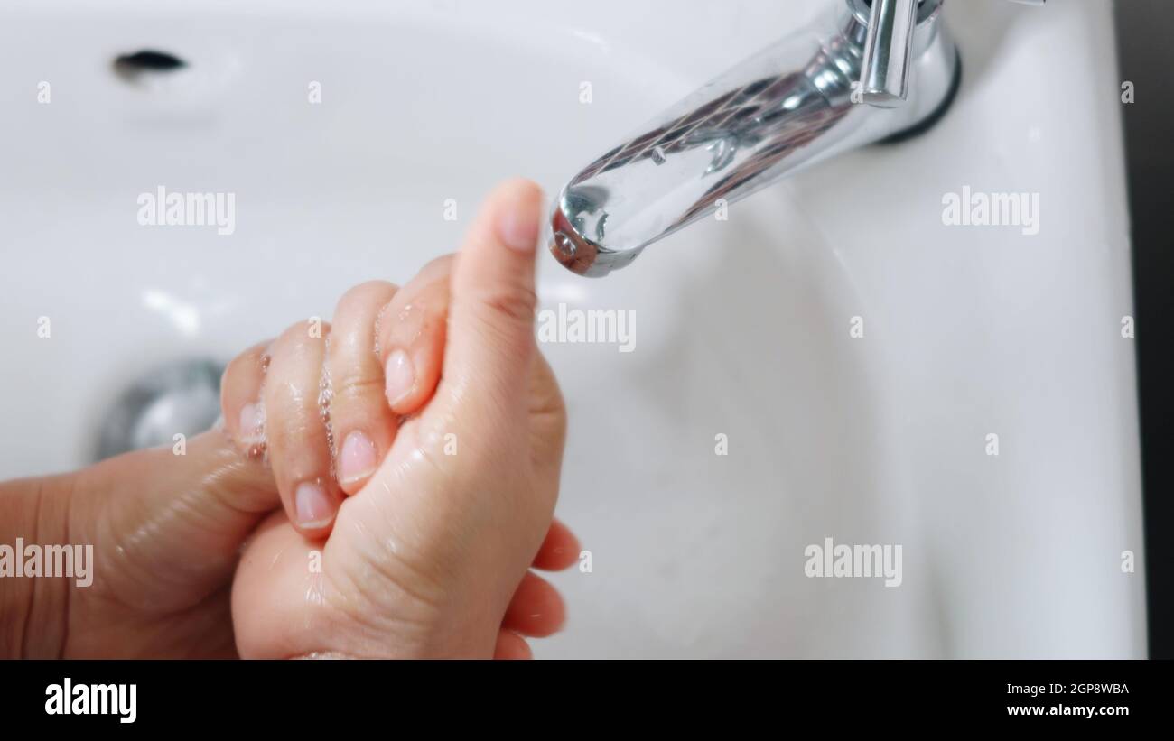 Closeup young woman hands using soap and washing hands under the water ...