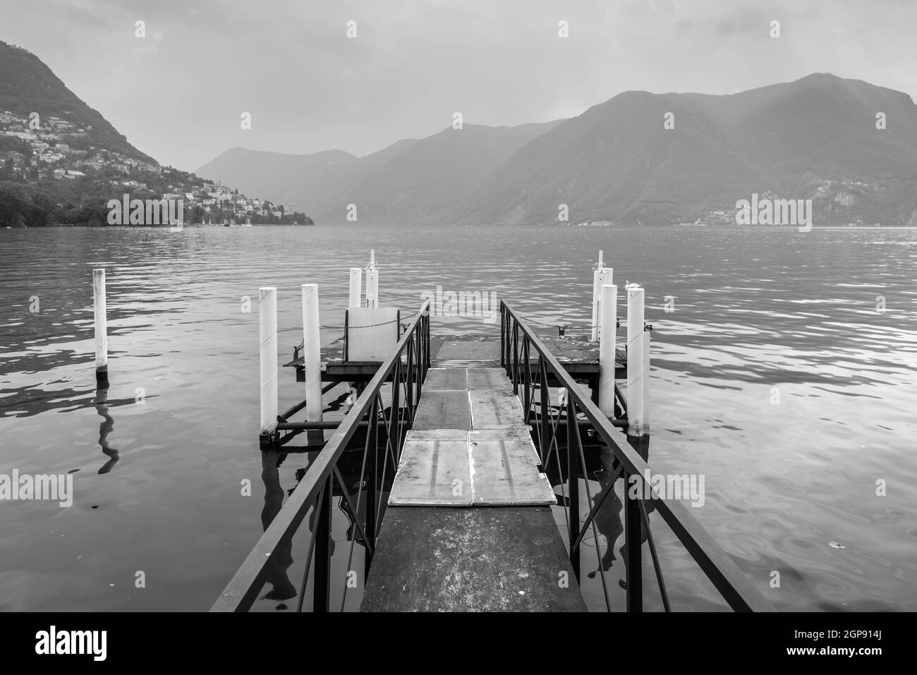 Boat pier on the Lake Lugano, Switzerland. Black and white photography. European vacation, travel and nautical concept. Stock Photo