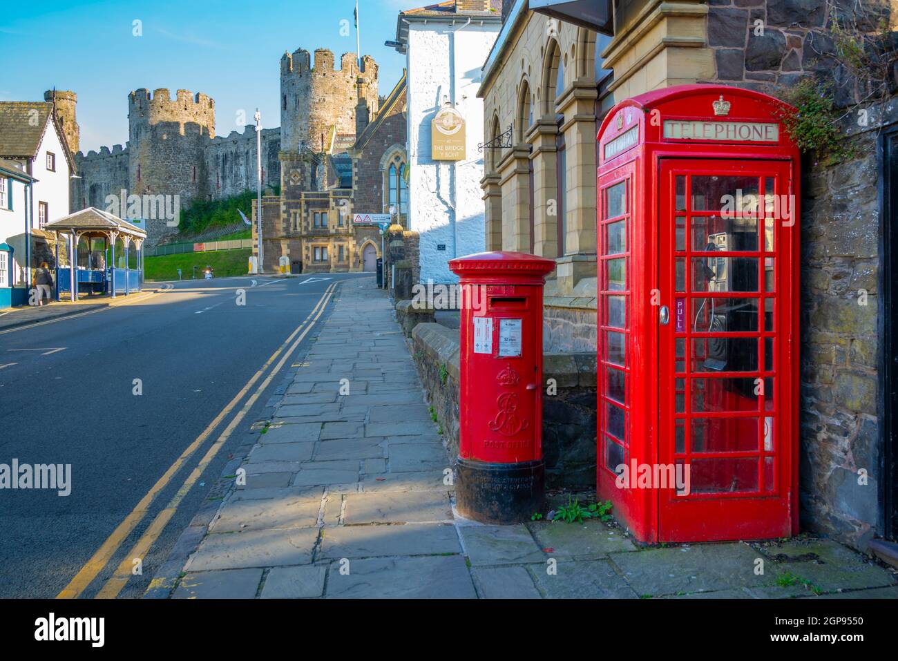 View of red telephone and post box with Conwy Castle visible in background, Conwy, Gwynedd, North Wales, United Kingdom, Europe Stock Photo