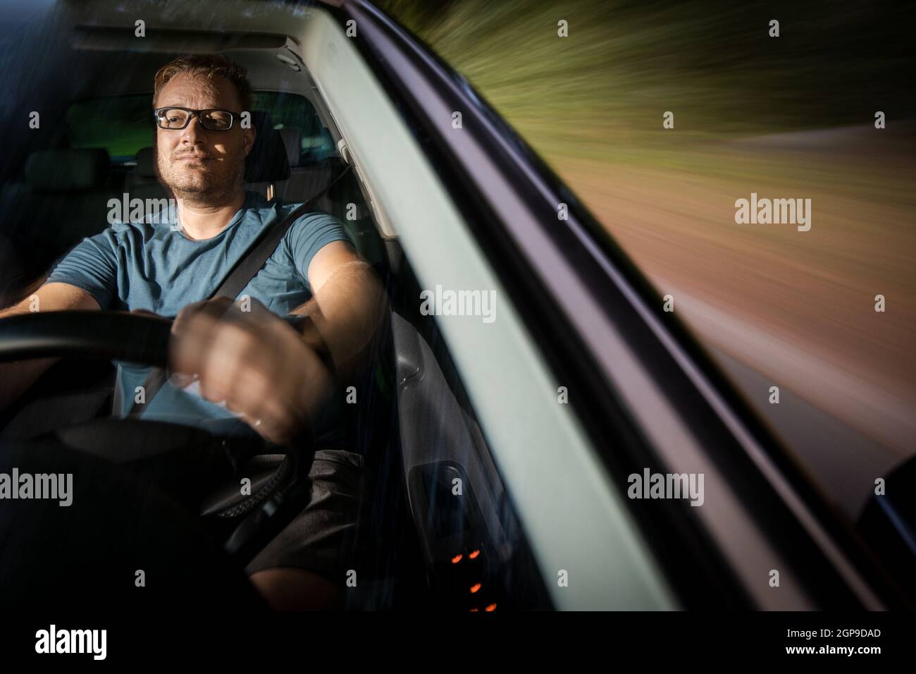Handsome young driver driving hic car fast yet safely on the road Stock Photo