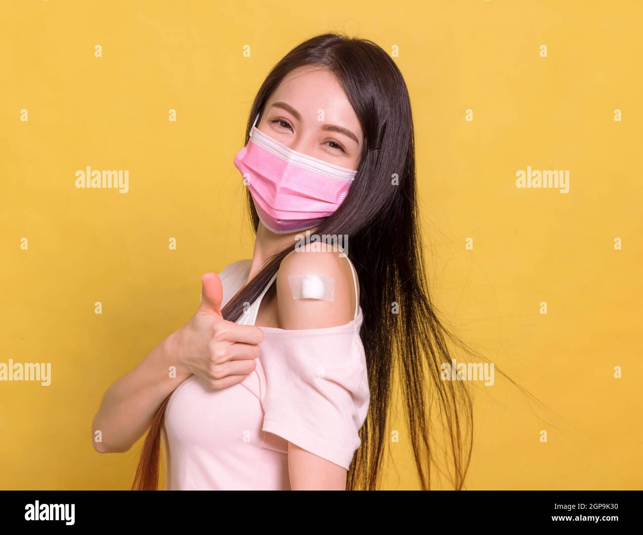 Young  woman  receive covid-19 anti virus vaccine and showing thumbs up Stock Photo