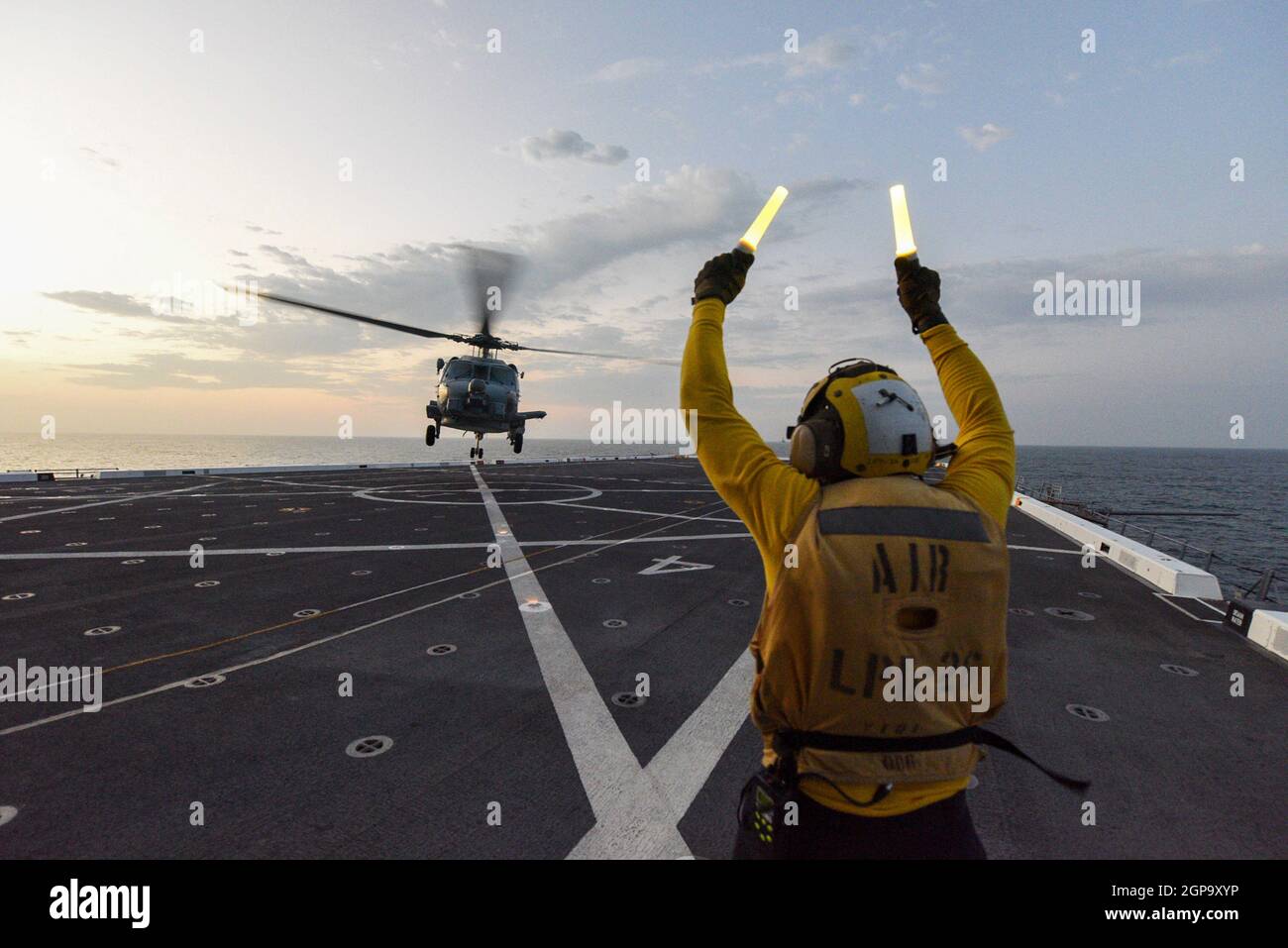 EASTERN PACIFIC OCEAN (Sept. 27, 2021) Aviation Boatswain’s Airman Kevon Lamont-Anderson, from Cleburn, Texas, assigned to the amphibious transport dock ship USS John P. Murtha (LPD 26) directs a MH-60R Sea Hawk helicopter attached to the “Scorpions” of Helicopter Maritime Strike Squadron (HSM) 49 to take off from flight deck during UNITAS LXII, Sept. 27, 2021.  UNITAS is the world’s longest-running maritime exercise. Hosted this year by Peru, it brings together multinational forces from 20 countries and includes 32 ships, four submarines, and 26 aircraft conducting operations off the coast of Stock Photo