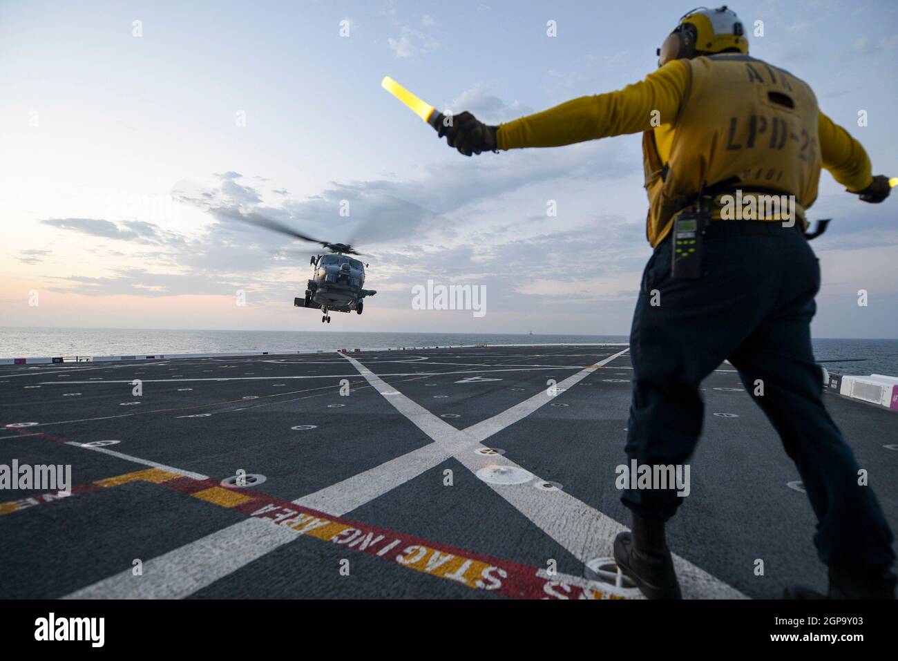 EASTERN PACIFIC OCEAN (Sept. 27, 2021) Aviation Boatswain’s Airman Kevon Lamont-Anderson, from Cleburn, Texas, assigned to amphibious transport dock ship USS John P. Murtha (LPD 26) directs a MH-60R Sea Hawk helicopter attached to the “Scorpions” of Helicopter Maritime Strike Squadron (HSM) 49 to land on the flight deck during UNITAS LXII, Sept. 27, 2021.  UNITAS is the world’s longest-running maritime exercise. Hosted this year by Peru, it brings together multinational forces from 20 countries and includes 32 ships, four submarines, and 26 aircraft conducting operations off the coast of Lima Stock Photo