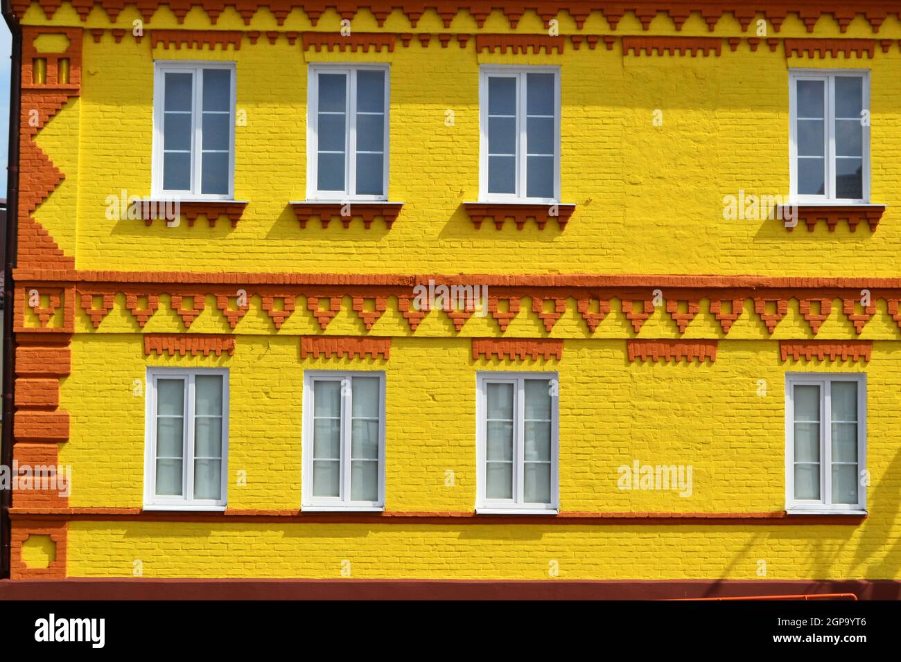 The facade of a house made of brick painted in yellow and windows ...