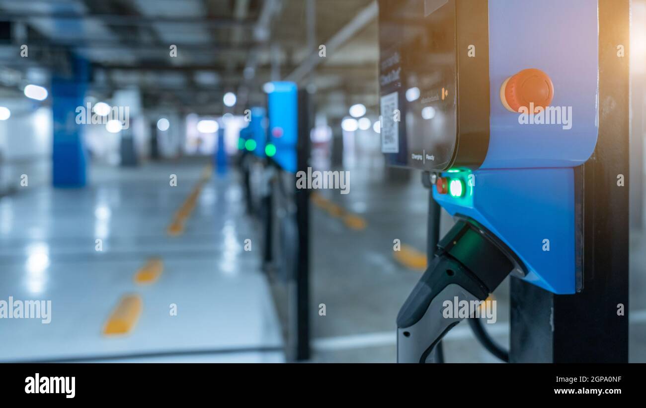Blurred electric car charging station for charge EV battery. Plug for vehicle with electric engine. EV charger. Clean energy. Charging point at car pa Stock Photo