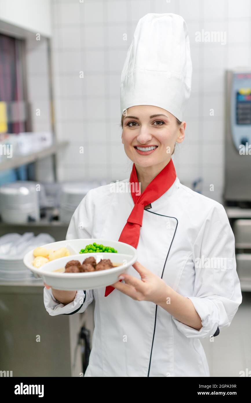 Proud cook showing plate with food in commercial kitchen of canteen ...