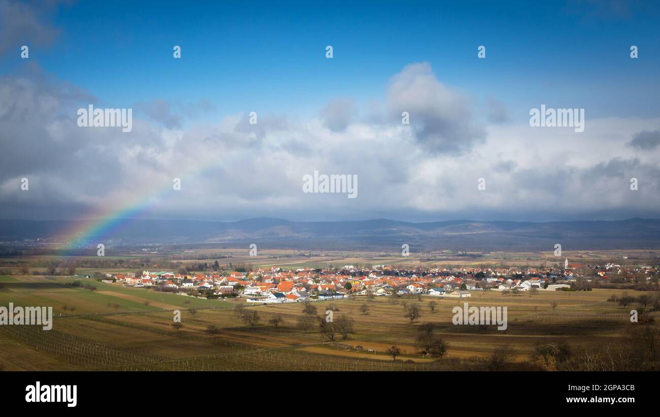 Small rainbow over village of Oslip in Burgenland Stock Photo