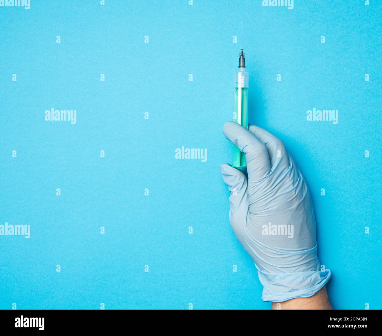 hand in blue latex gloves hold a plastic syringe on a blue background ...