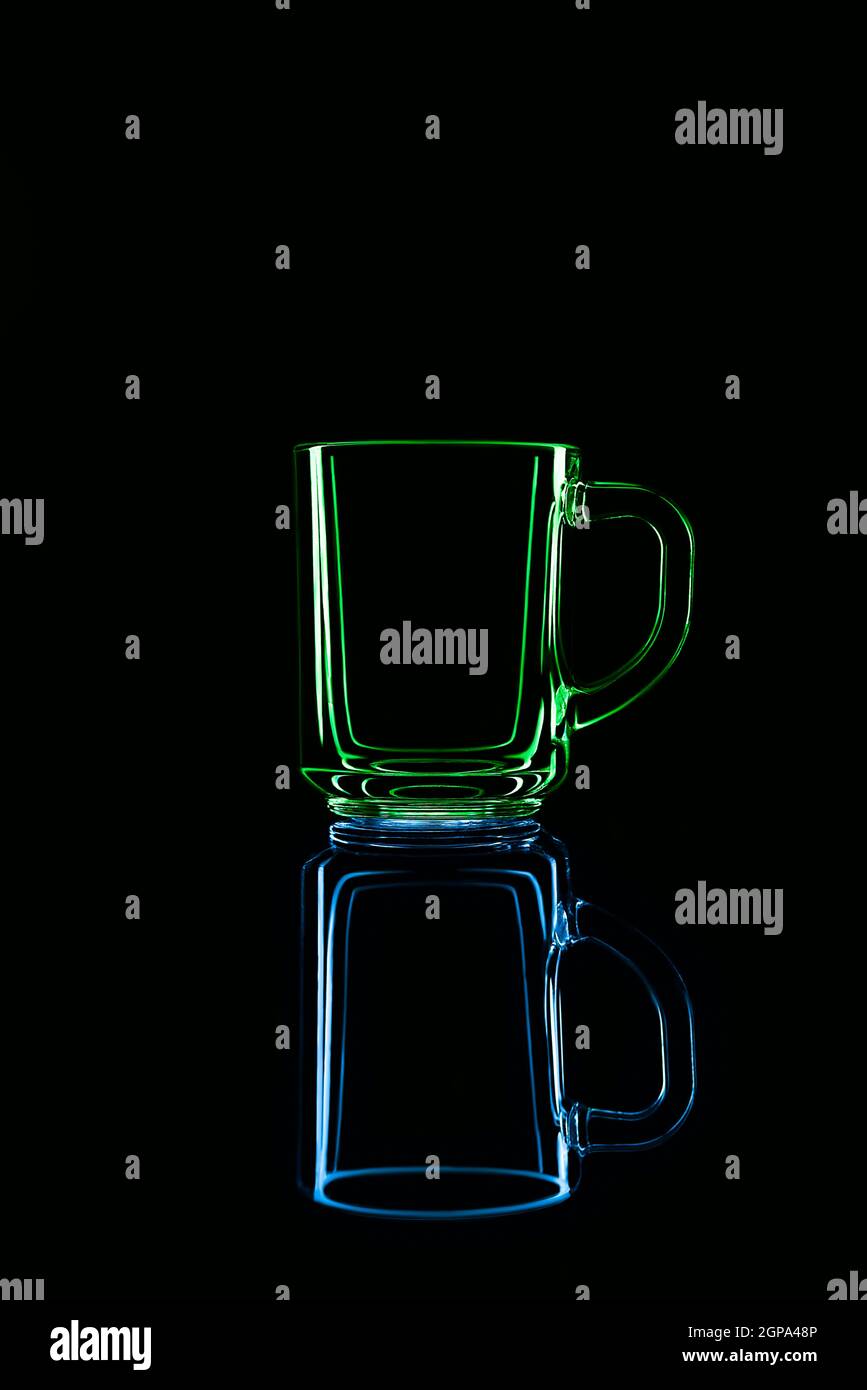 Just a glass on a black background with a reflection. Green and blue ...
