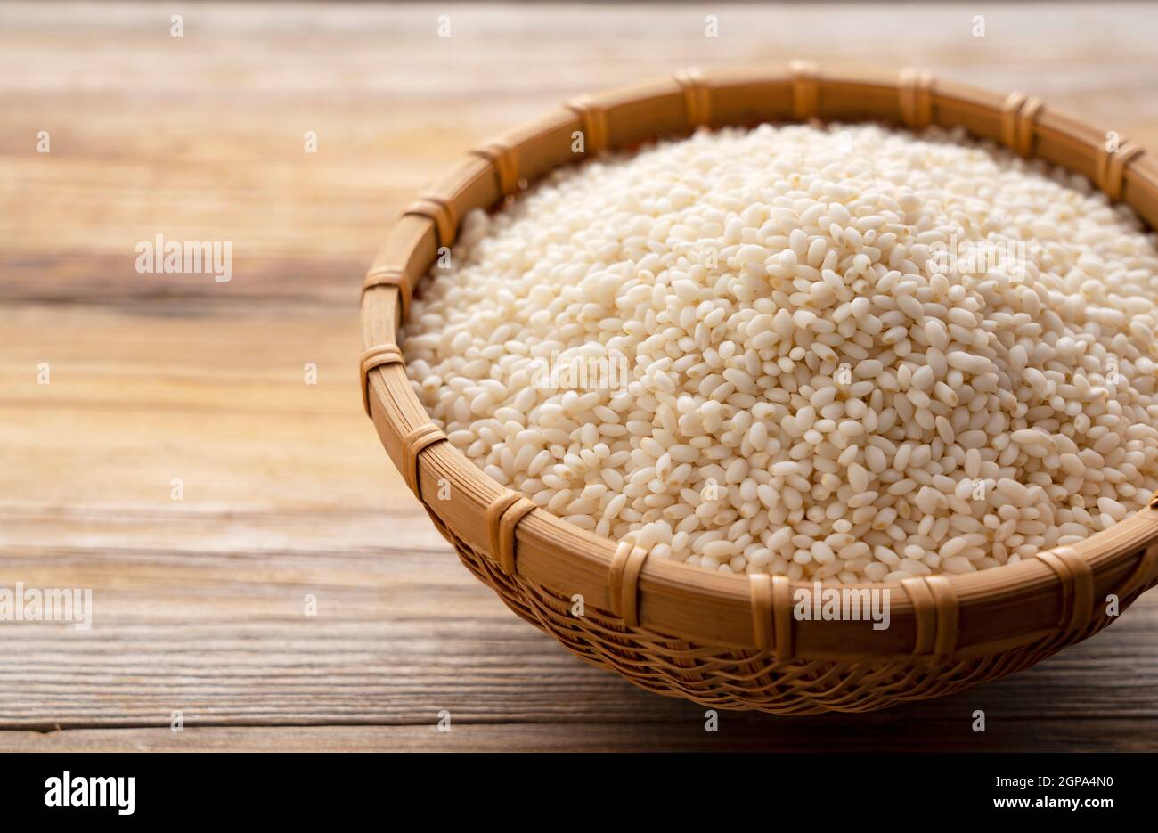Glutinous rice in a bamboo colander set against a background of trees ...