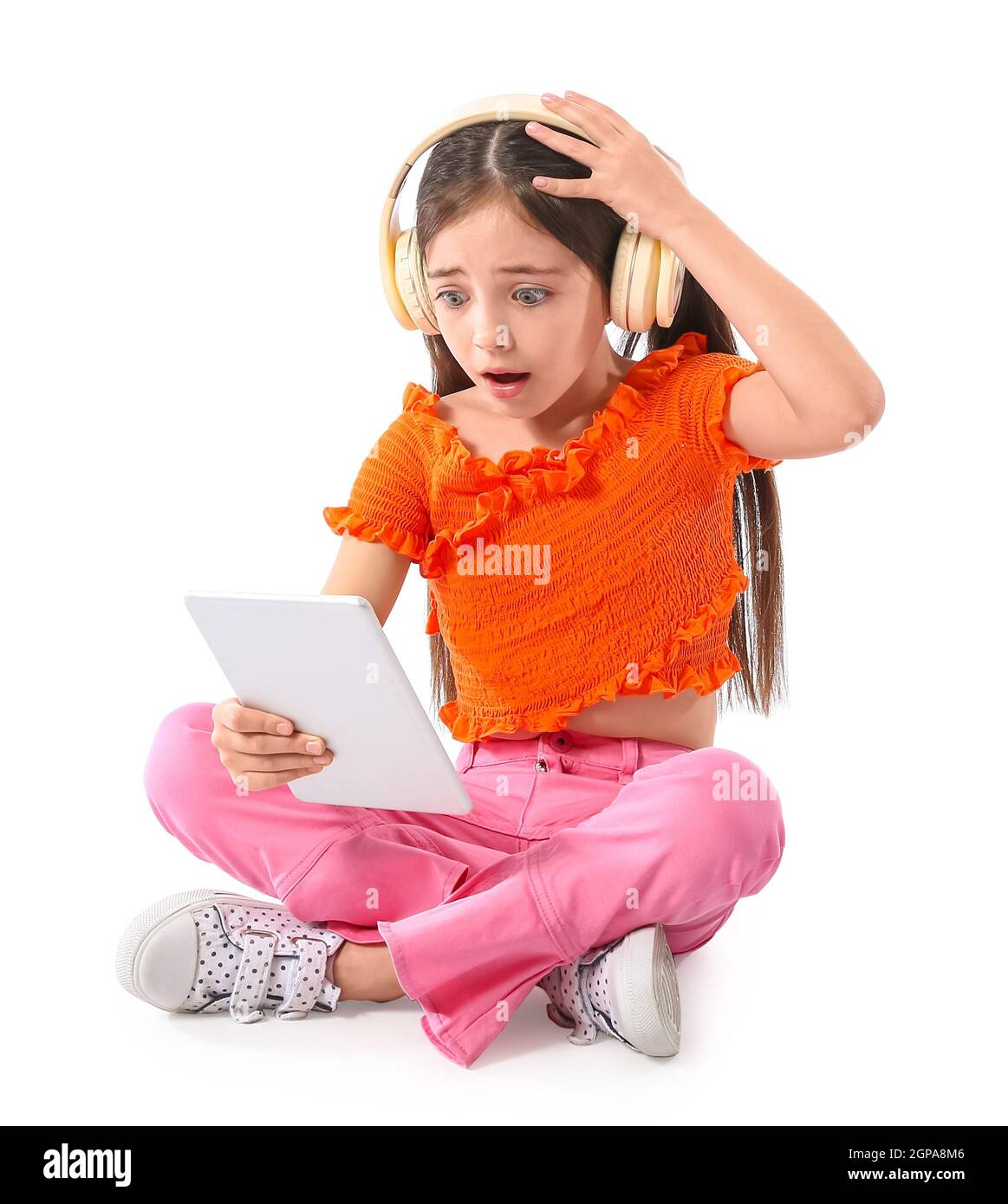 Shocked little girl with headphones and tablet computer on white background Stock Photo