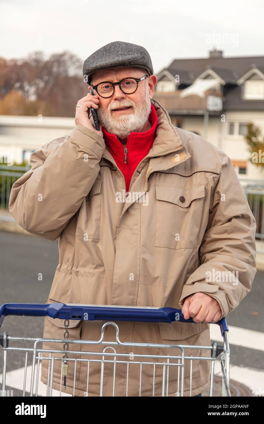 Senior with winter cloth using cell phone while he is pushing is ...