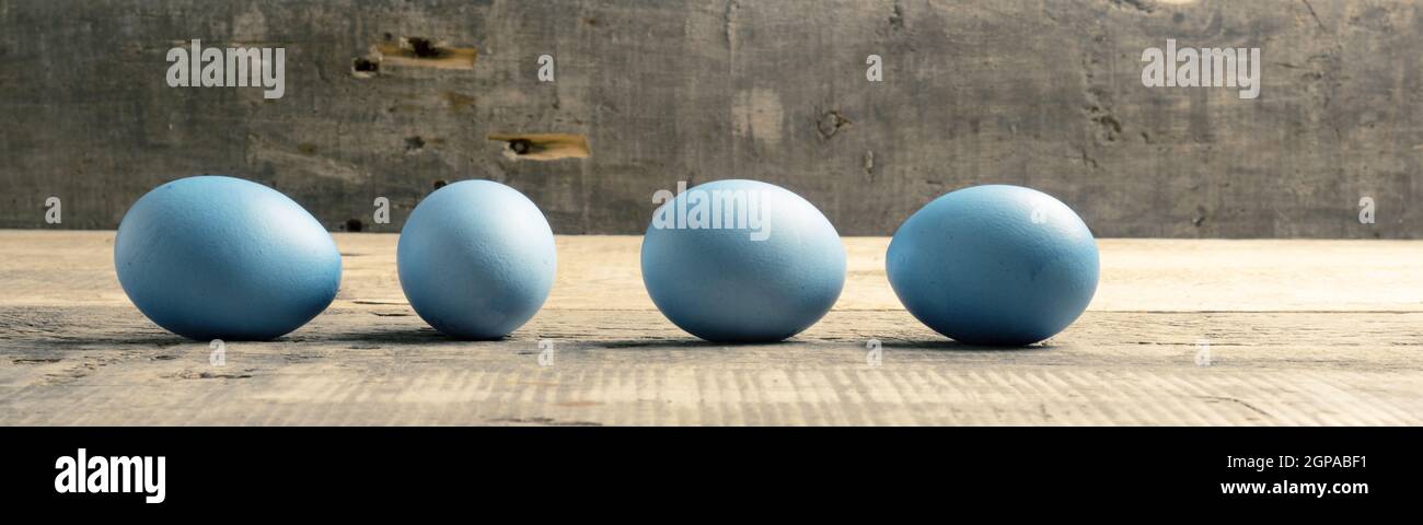 Naturally colored organic eggs in a row on a rustic table with space for text, Easter background Stock Photo