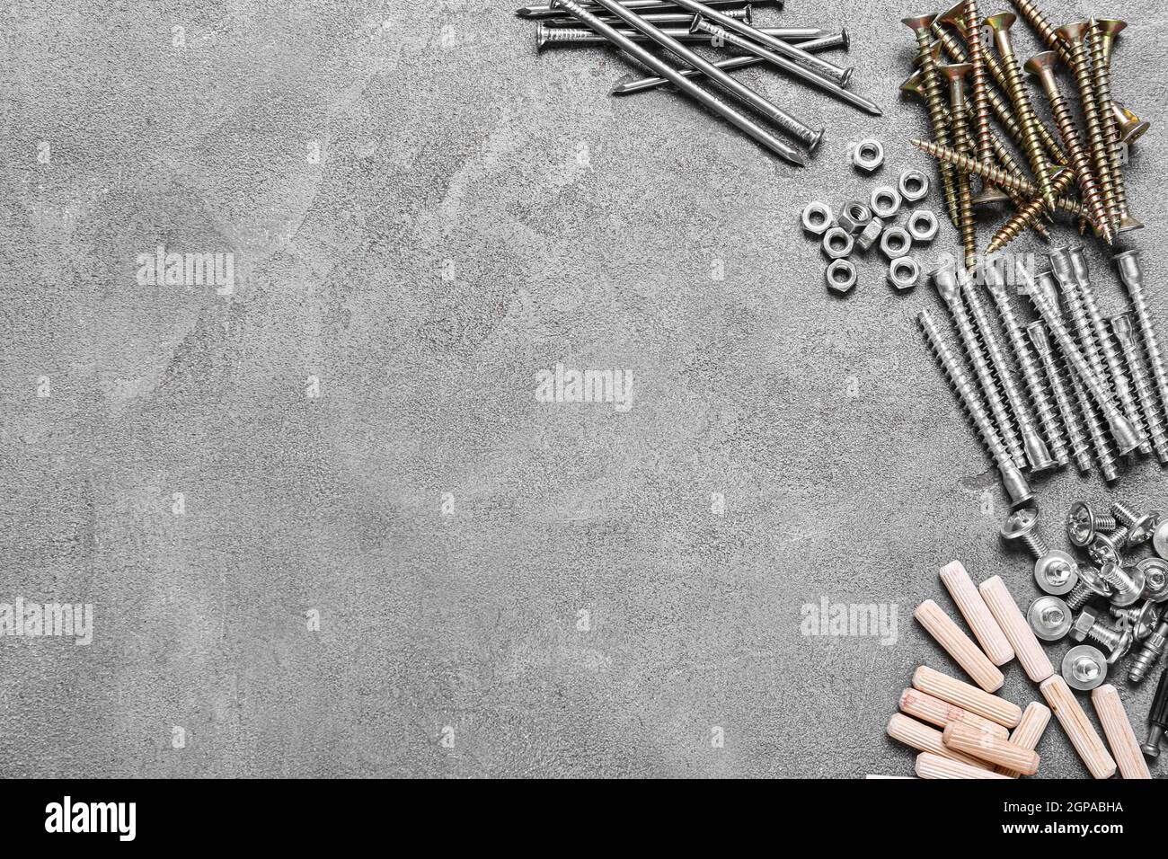 Different nuts, bolts, screws, nails and dowels on grey background