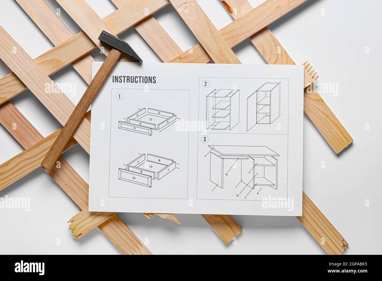 Furniture assembling instructions, hammer and wooden planks on white