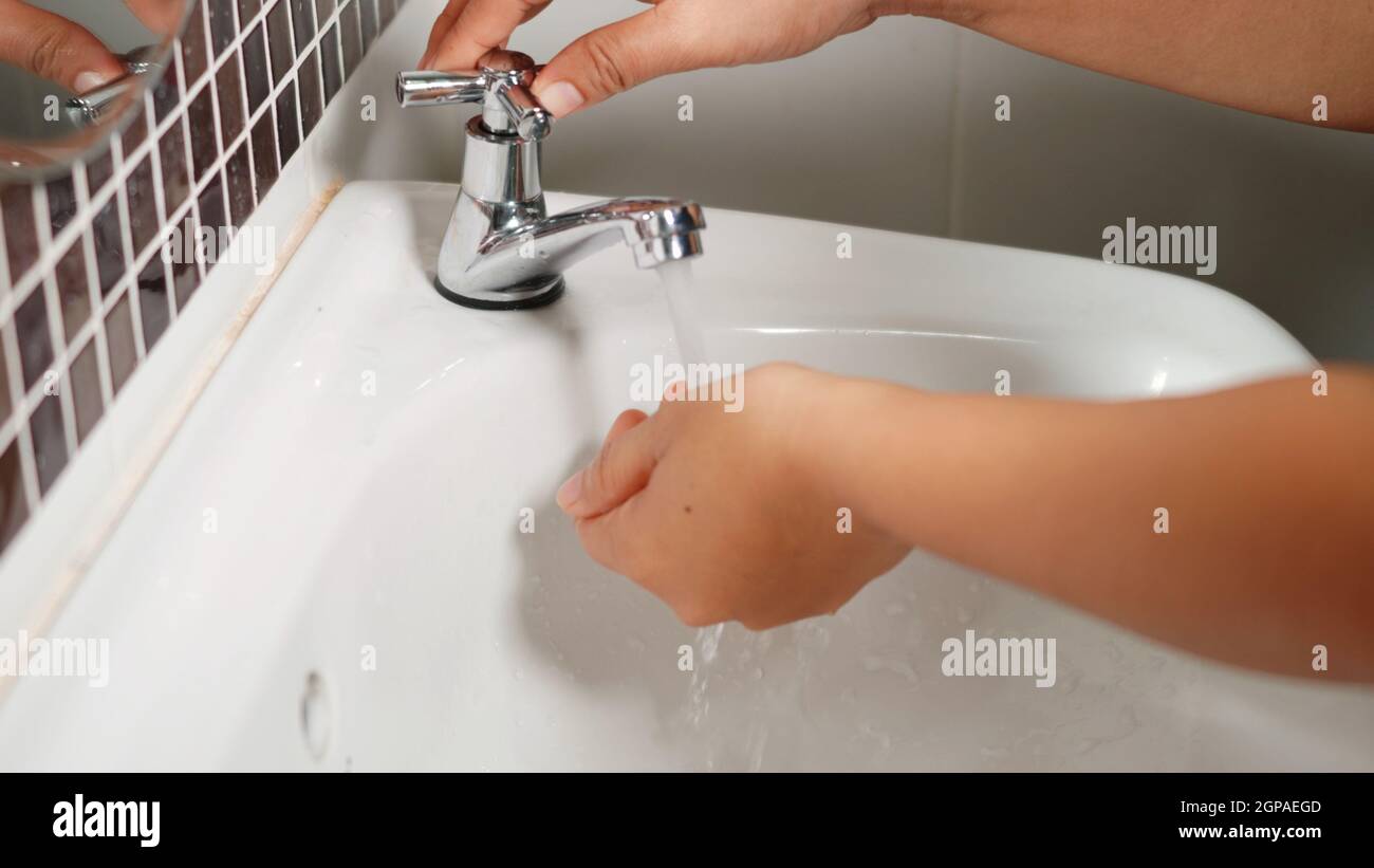 Closeup young woman hands using soap and washing hands under the water ...