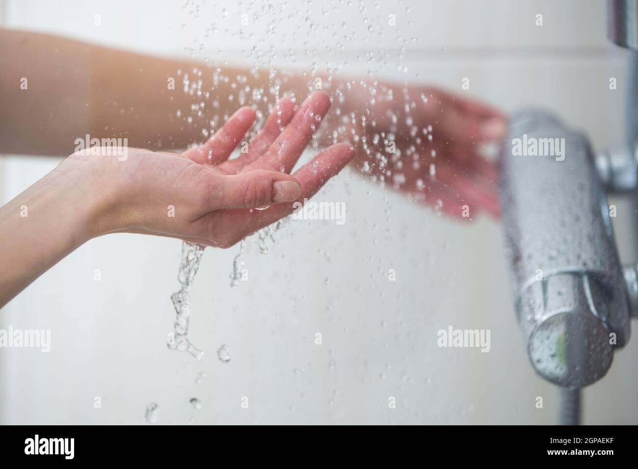 Woman taking a shower at home female hands tryimg the temperature of