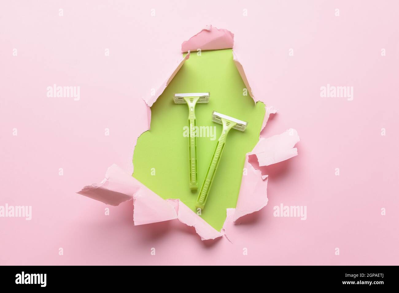 Safety razors visible through torn color paper Stock Photo Alamy