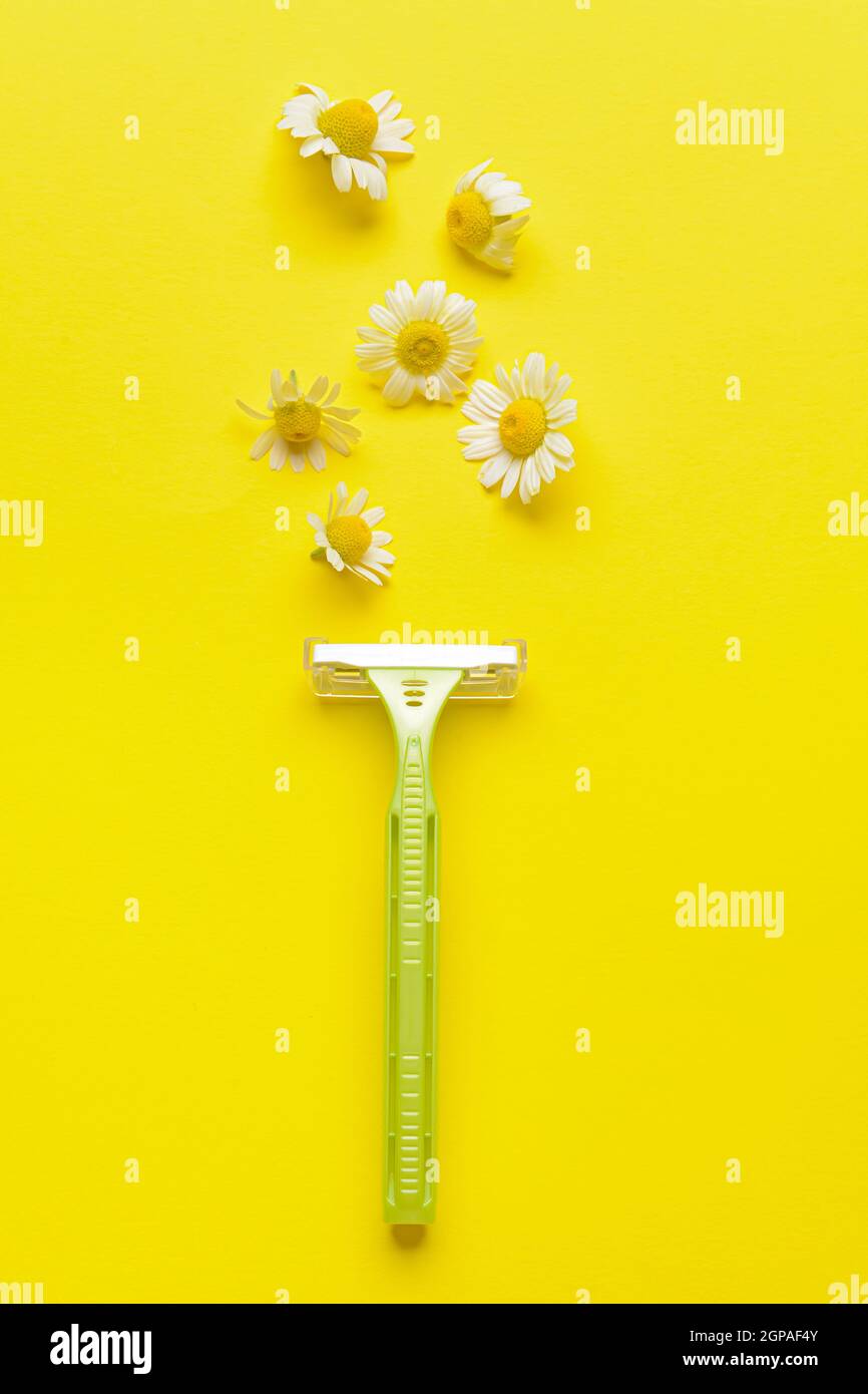 Safety razor and chamomile flowers on yellow background Stock Photo - Alamy
